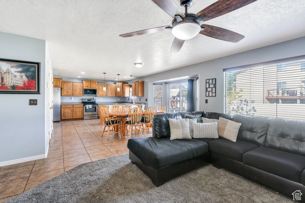 Living area featuring a textured ceiling, light tile patterned floors, ceiling fan, and recessed lighting