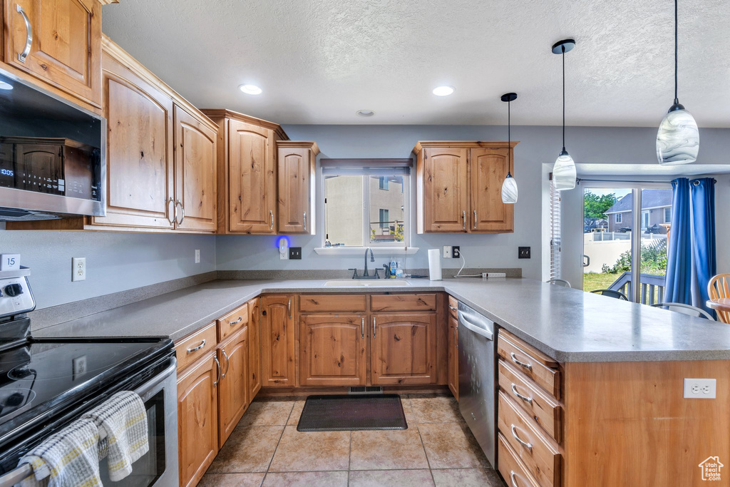 Kitchen with stainless steel appliances, a peninsula, a textured ceiling, recessed lighting, and pendant lighting