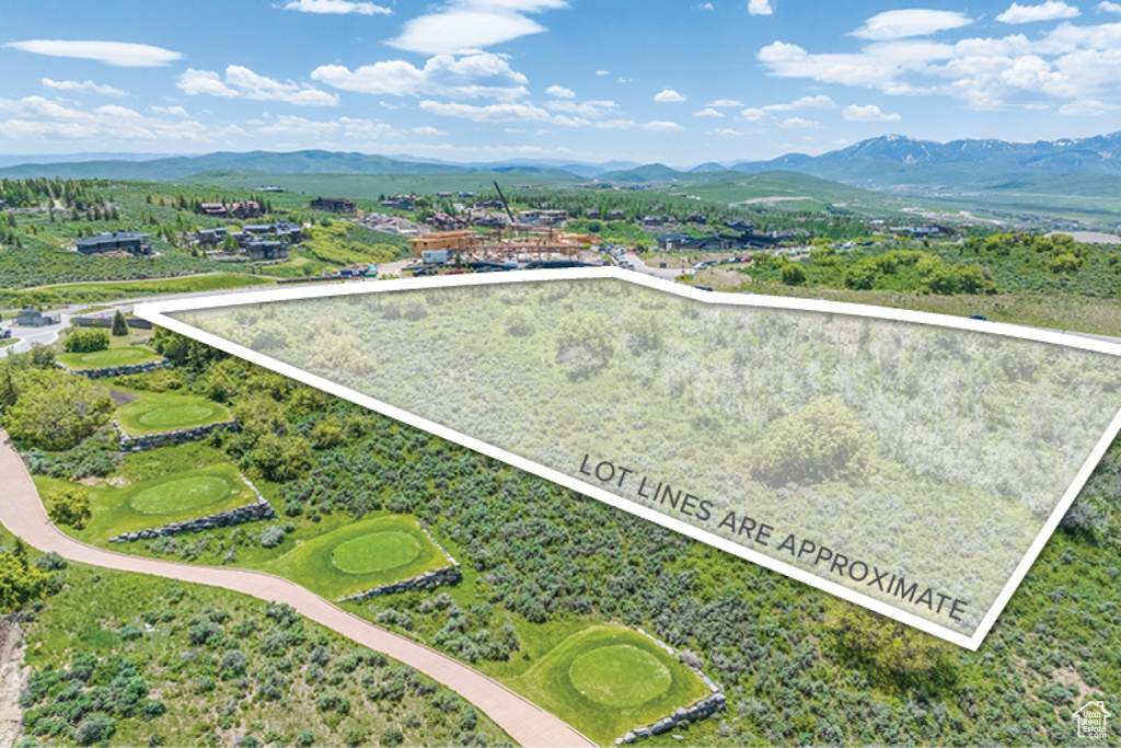 Aerial view of property and surrounding area featuring property boundaries highlighted and a mountainous background