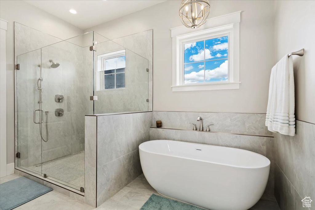 Full bath with a freestanding tub, a stall shower, tile walls, and wainscoting