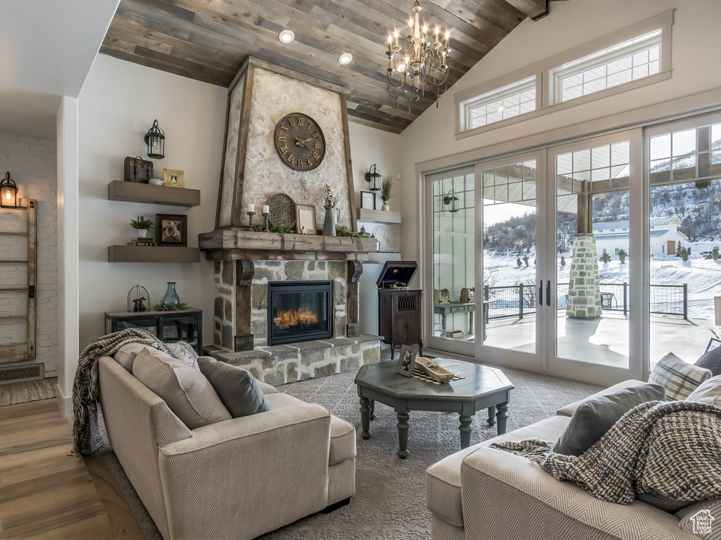 Living room featuring a chandelier, a stone fireplace, wood finished floors, and high vaulted ceiling