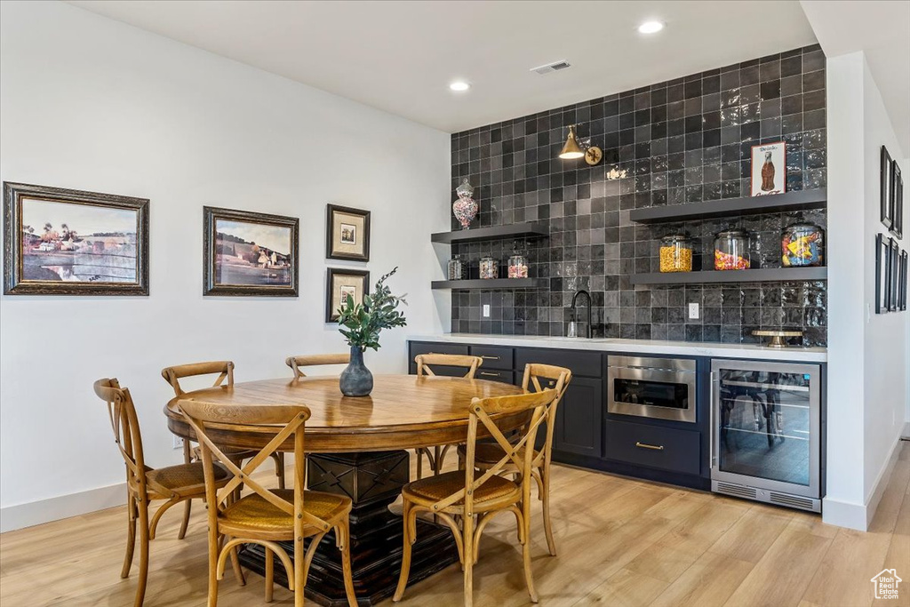 Indoor bar featuring wine cooler, tasteful backsplash, light wood finished floors, and recessed lighting