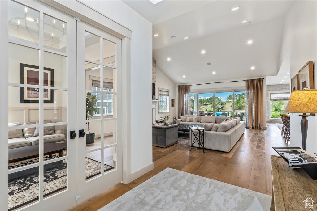 Living room with wood finished floors, high vaulted ceiling, french doors, and recessed lighting