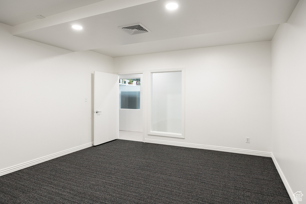 Empty room with dark colored carpet and recessed lighting