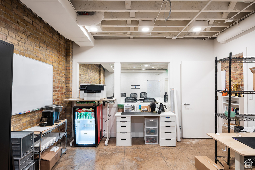 Home office featuring brick wall and unfinished concrete floors