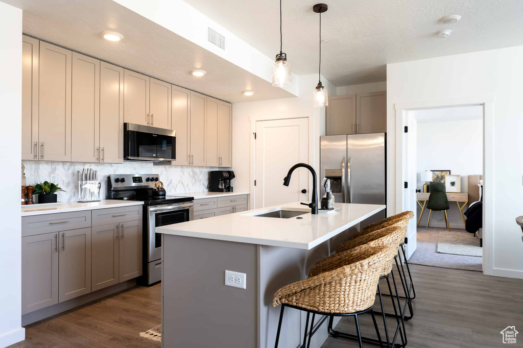 Kitchen with appliances with stainless steel finishes, dark wood-type flooring, backsplash, a kitchen bar, and recessed lighting