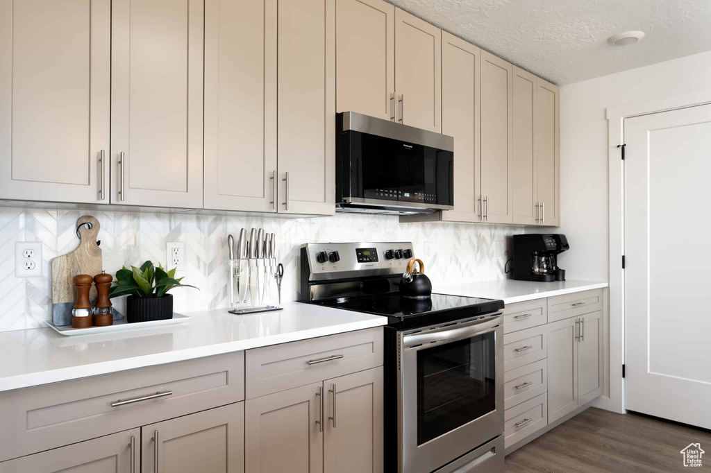Kitchen featuring appliances with stainless steel finishes, light countertops, backsplash, gray cabinetry, and a textured ceiling