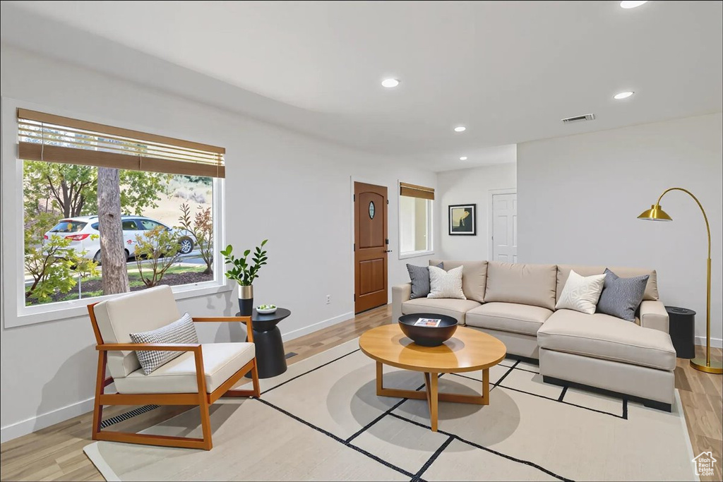 Living area with healthy amount of natural light, recessed lighting, and light wood-style floors