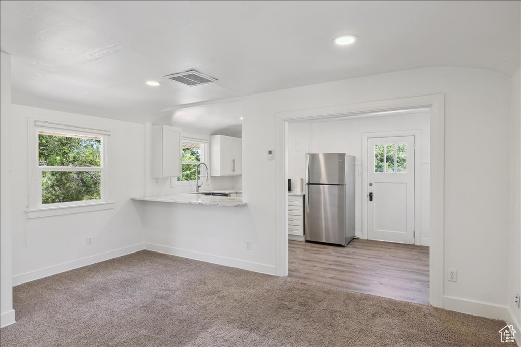 Kitchen with freestanding refrigerator, white cabinetry, light carpet, plenty of natural light, and recessed lighting