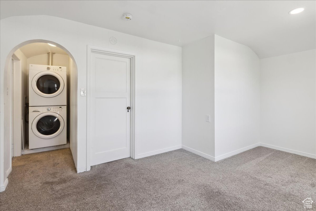 Washroom with stacked washer / dryer, carpet flooring, and arched walkways