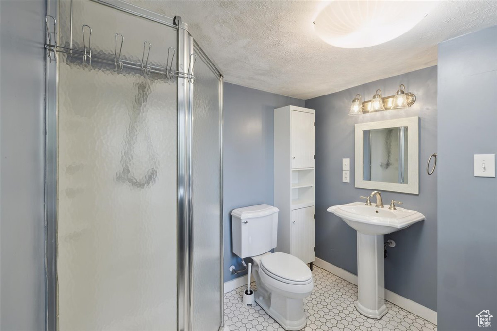 Bathroom featuring a shower stall and a textured ceiling