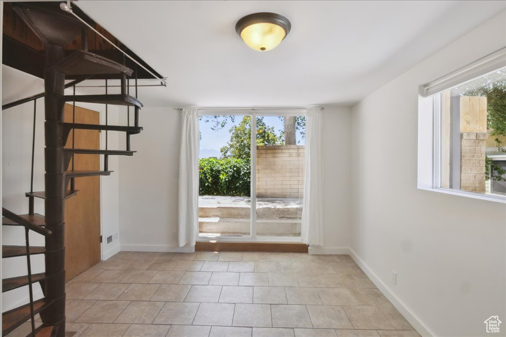 Unfurnished room featuring plenty of natural light, stairway, and light tile patterned flooring