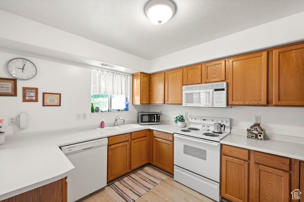 Kitchen with white appliances, brown cabinets, and light countertops