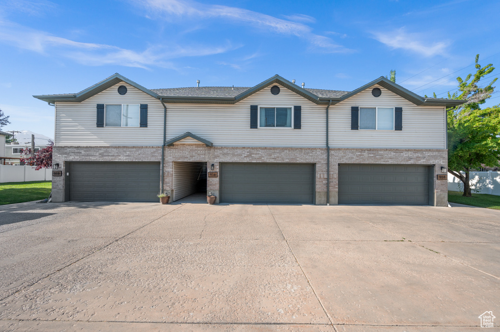 Multi unit property with concrete driveway, an attached garage, and brick siding