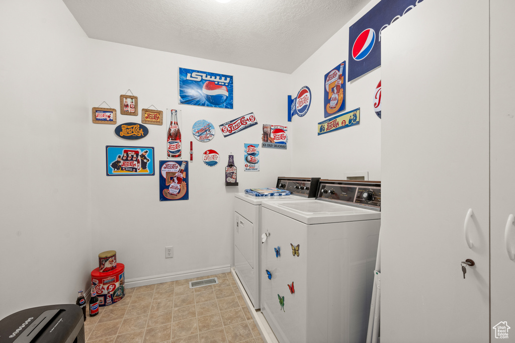 Laundry area featuring washer and clothes dryer and a textured ceiling