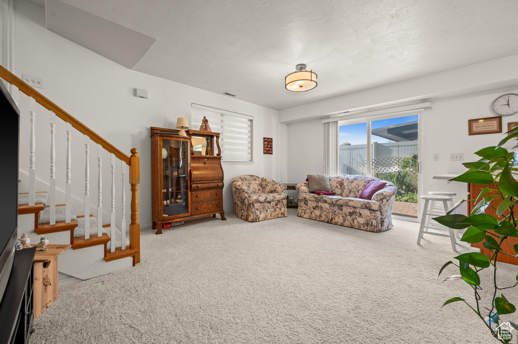 Carpeted living area with stairs