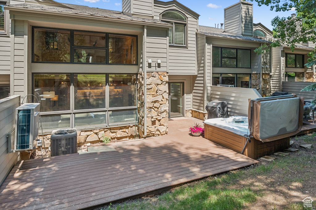 Wooden deck with a covered hot tub and area for grilling