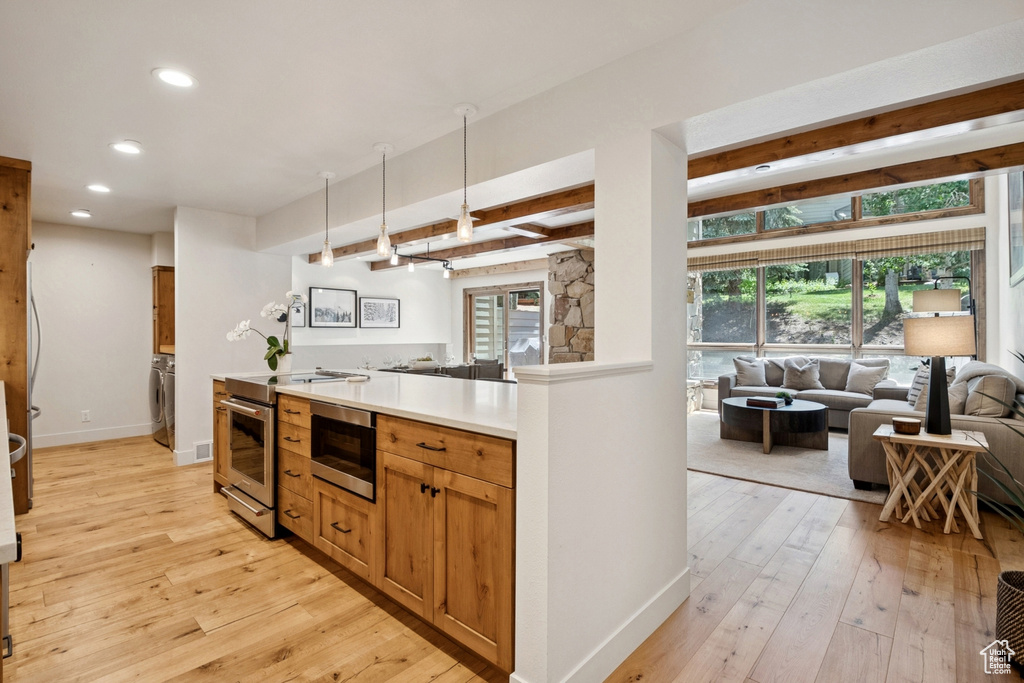 Kitchen featuring open floor plan, recessed lighting, stainless steel appliances, light wood-type flooring, and beam ceiling