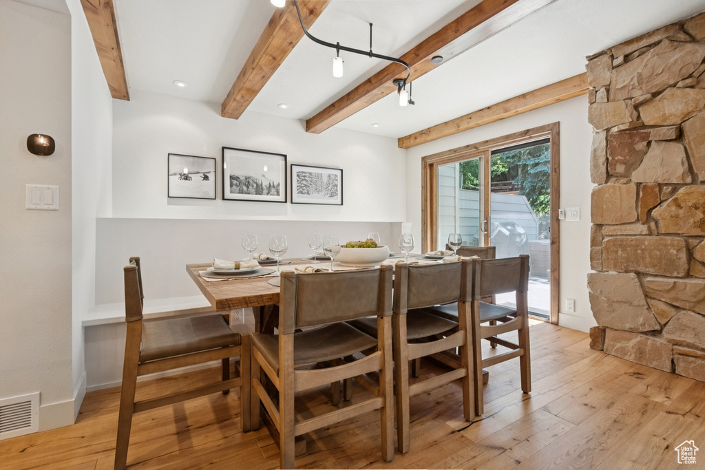 Dining space featuring light wood-type flooring and beamed ceiling