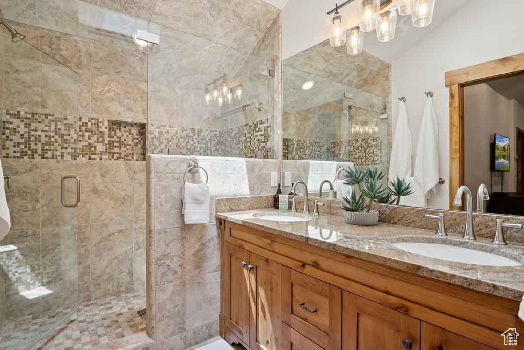 Bathroom featuring double vanity, a shower stall, and lofted ceiling