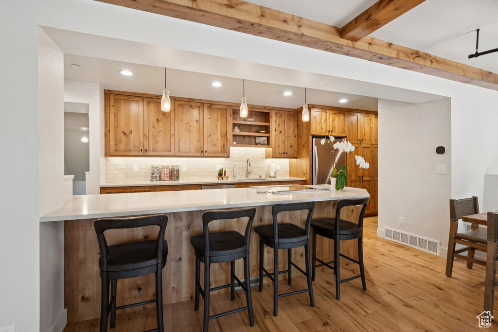 Kitchen featuring stainless steel appliances, light wood finished floors, backsplash, light countertops, and recessed lighting