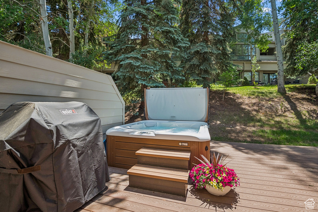 Wooden terrace with a hot tub and grilling area