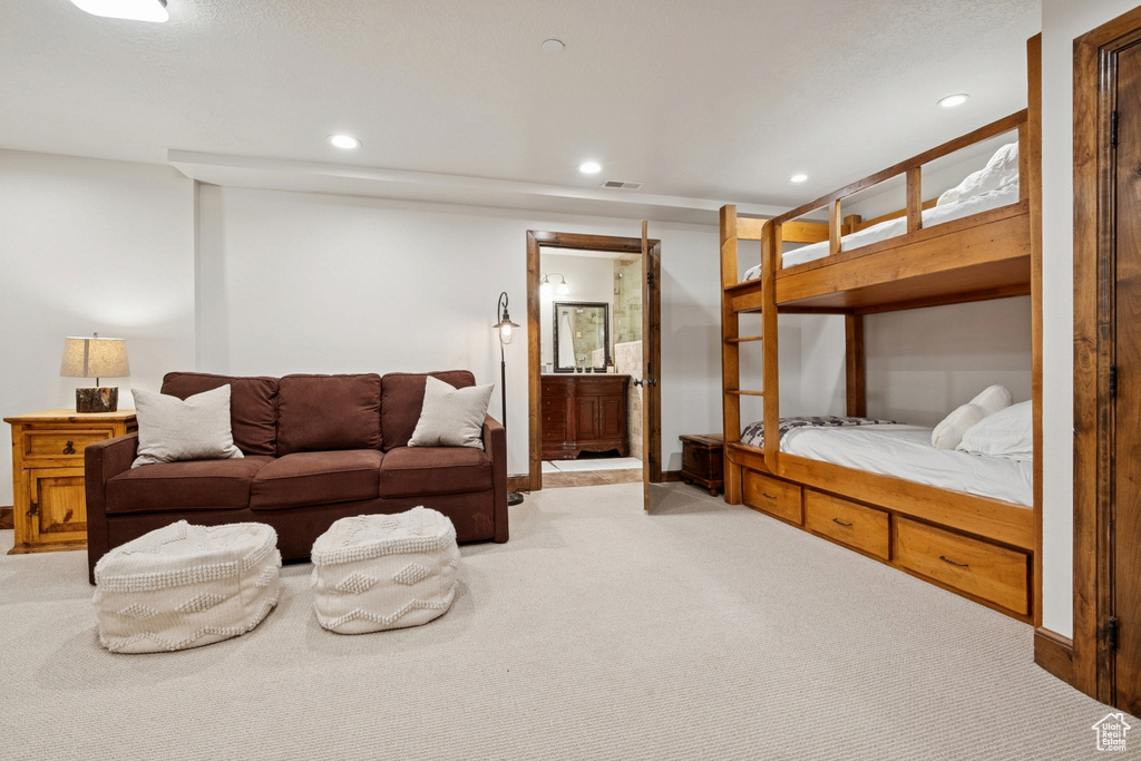 Bedroom featuring light colored carpet, recessed lighting, and ensuite bath