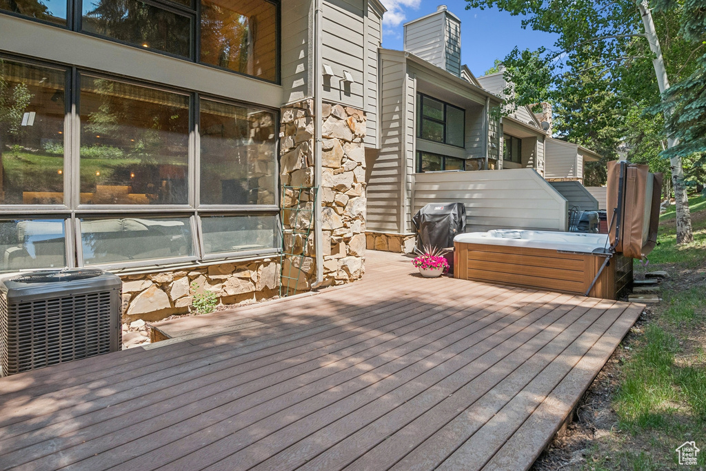 Wooden terrace featuring a hot tub and area for grilling