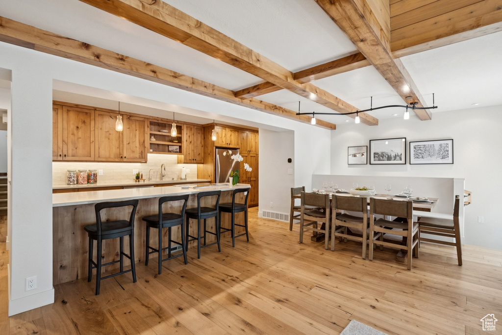 Dining room with beamed ceiling, light wood-type flooring, and wet bar