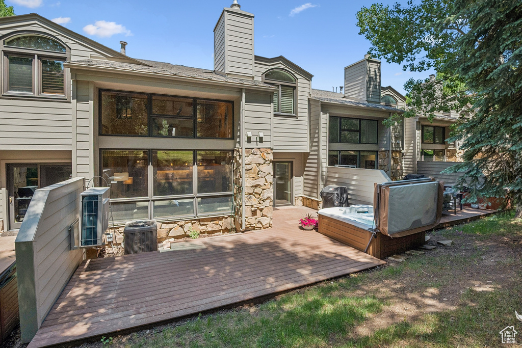 Back of property with a chimney, a deck, and stone siding
