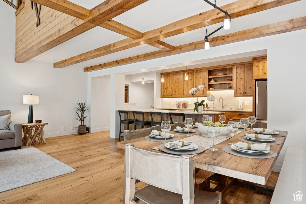 Dining room with beam ceiling and light wood-style floors