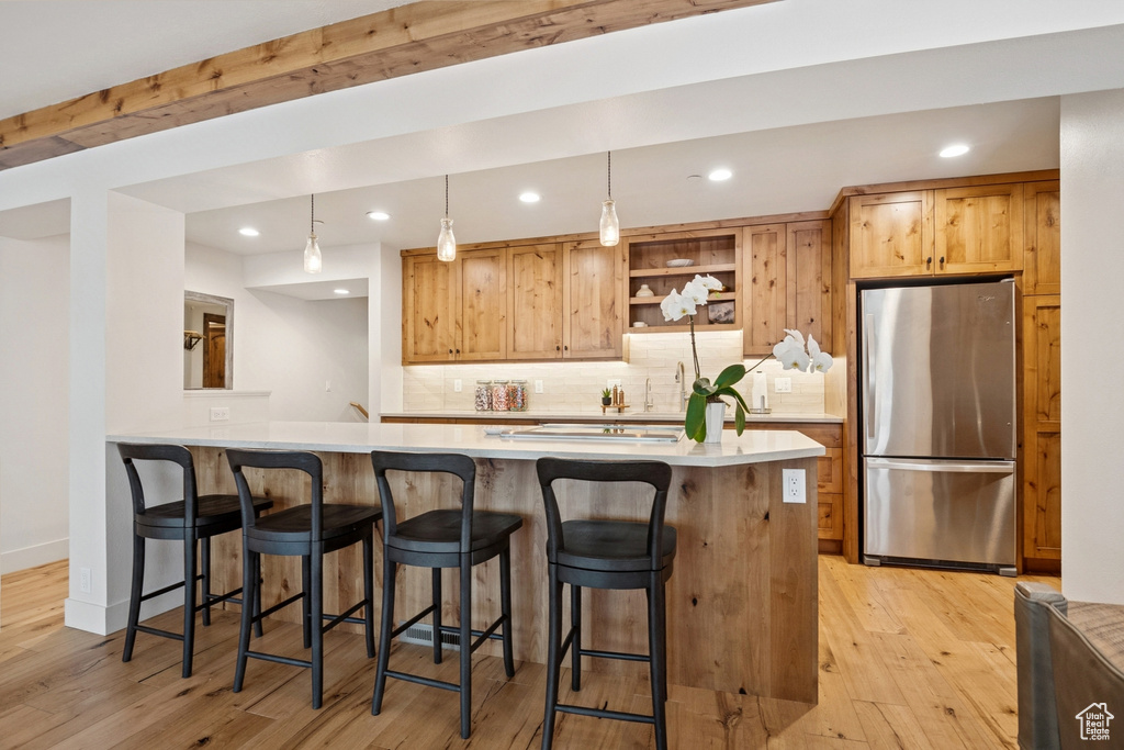 Kitchen with freestanding refrigerator, recessed lighting, light wood finished floors, tasteful backsplash, and light countertops