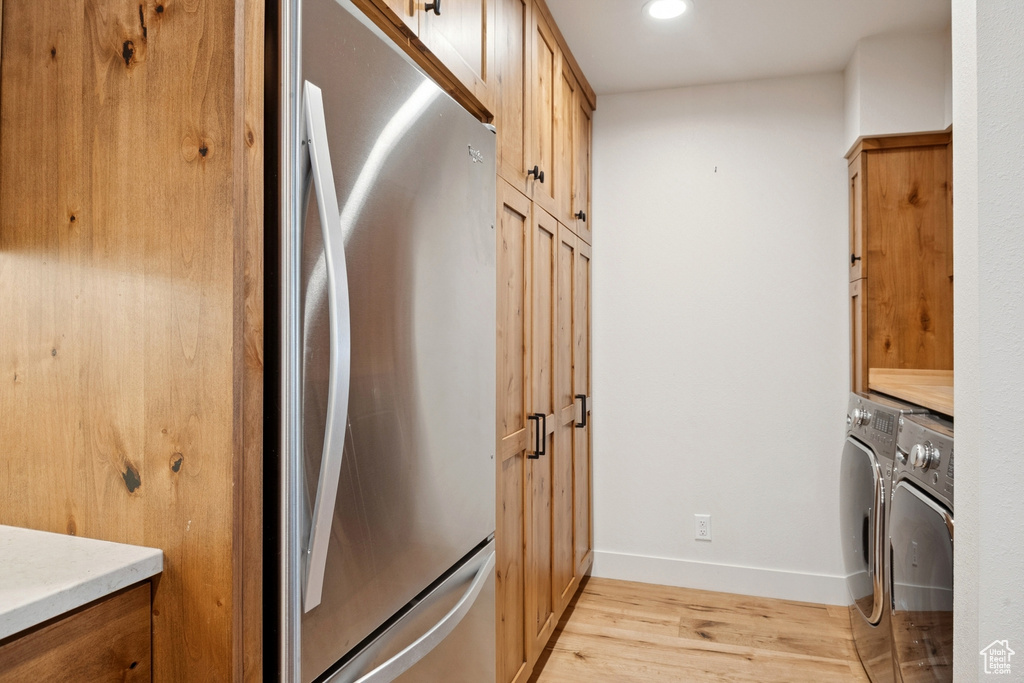 Laundry room with washing machine and clothes dryer, light wood-style floors, cabinet space, and recessed lighting