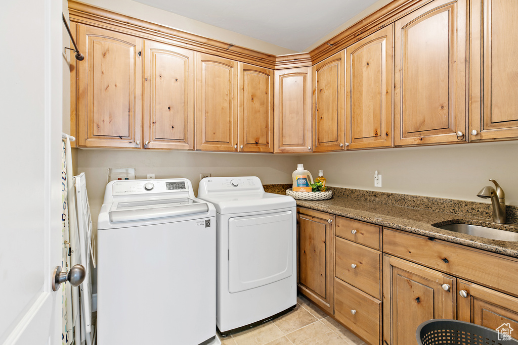 Laundry room featuring washing machine and dryer, cabinet space, and light tile patterned floors