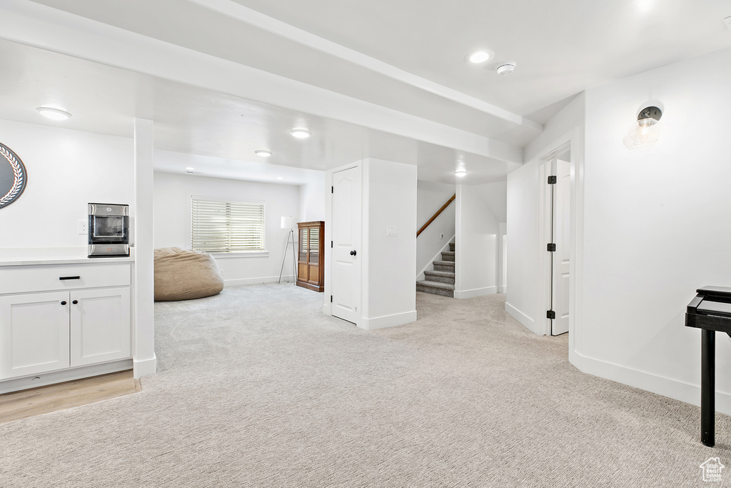 Basement with stairway and light carpet