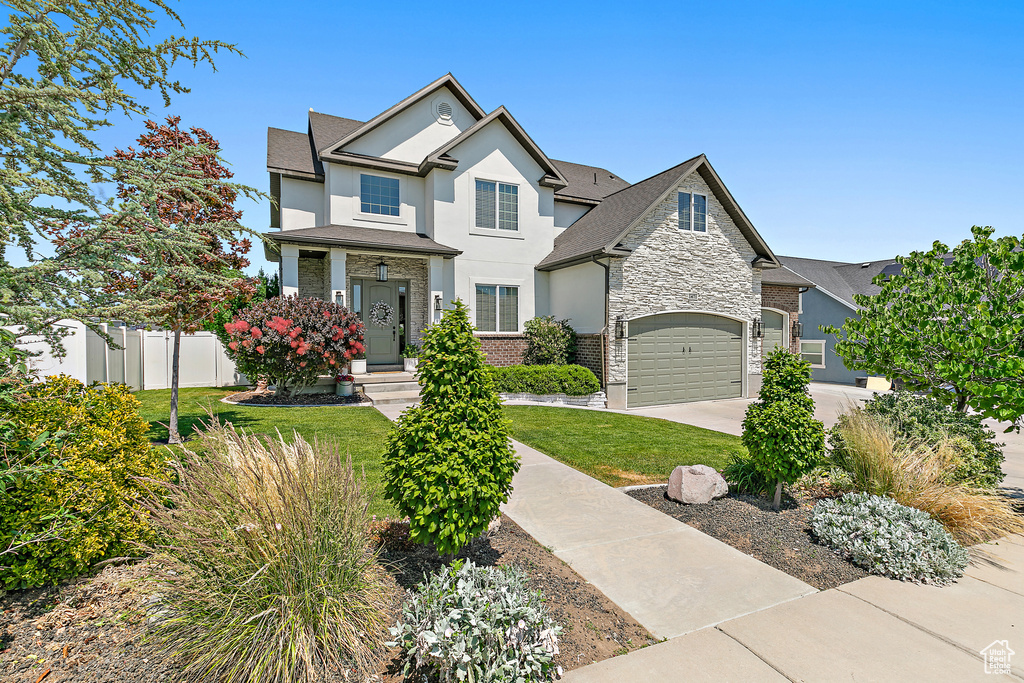 View of front of house featuring stone siding, driveway, stucco siding, and a shingled roof