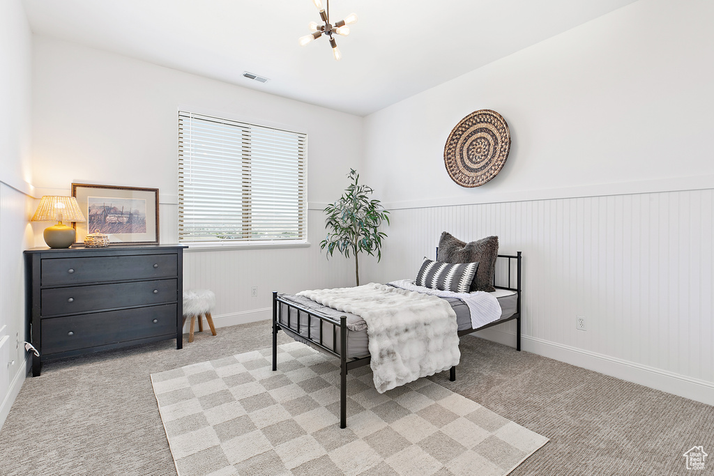 Carpeted bedroom with a chandelier and wainscoting