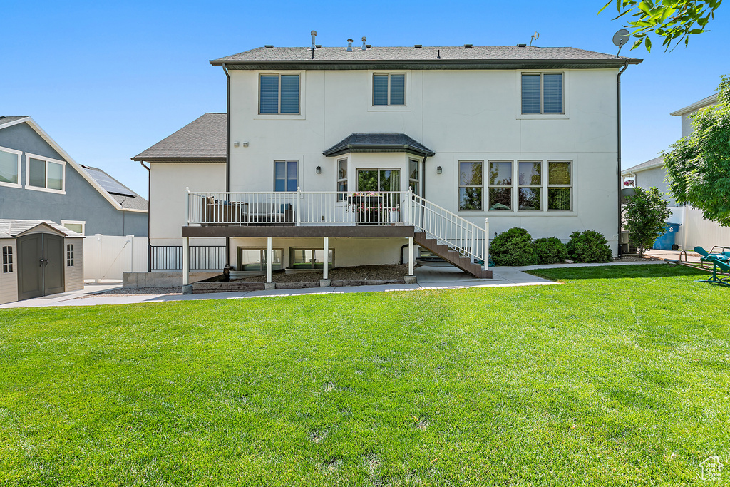 Rear view of house with a wooden deck, a patio area, stucco siding, stairway, and a storage shed