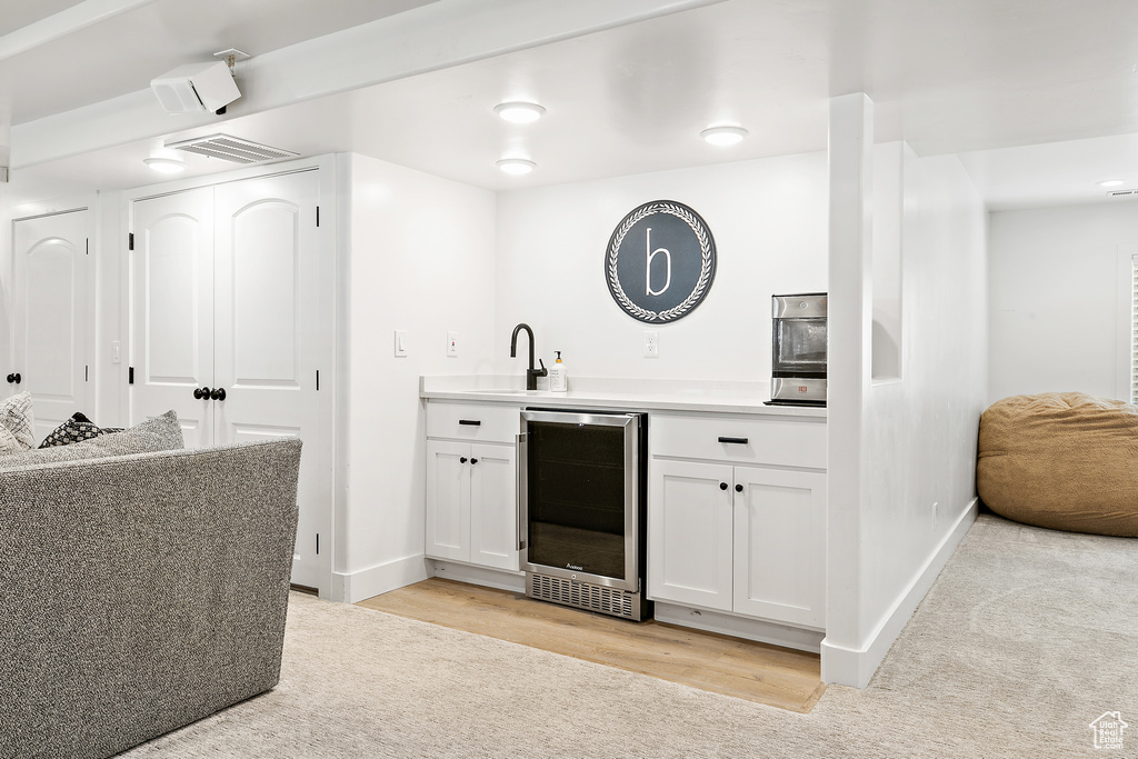 Indoor wet bar featuring wine cooler and light wood finished floors