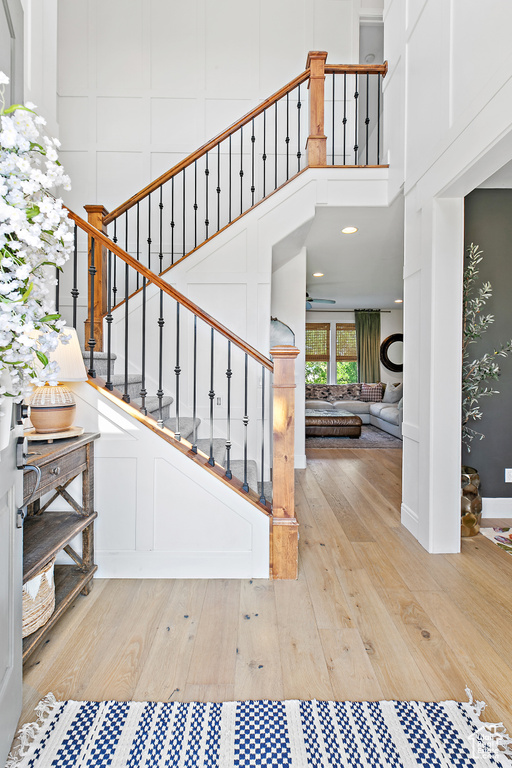 Stairs with wood finished floors, a decorative wall, and a towering ceiling