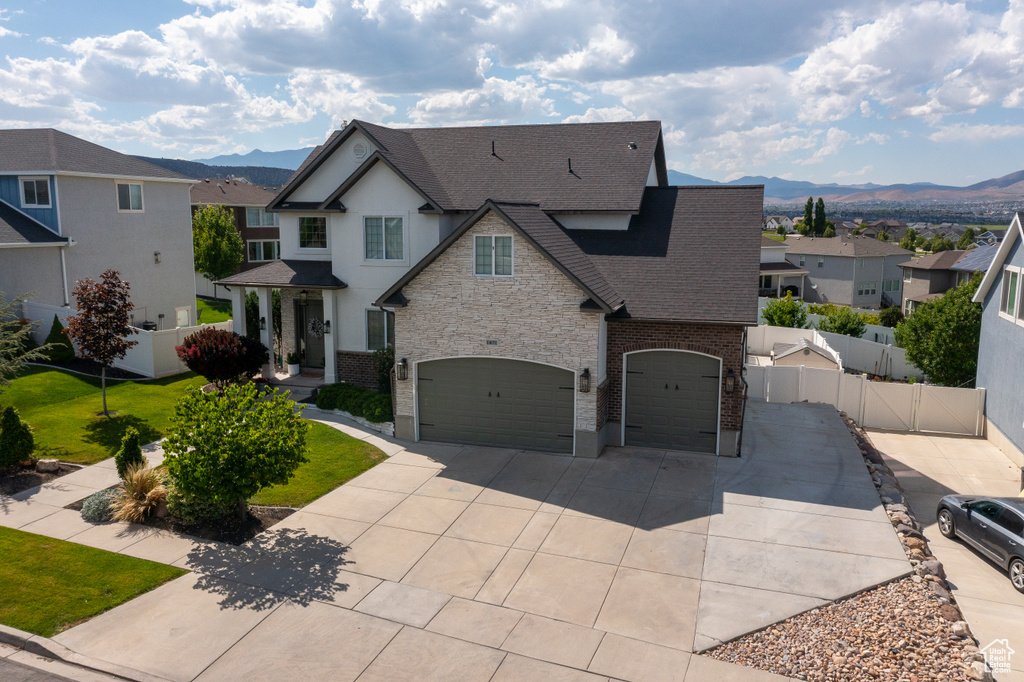 View of front facade featuring a shingled roof, a mountain view, concrete driveway, and an attached garage