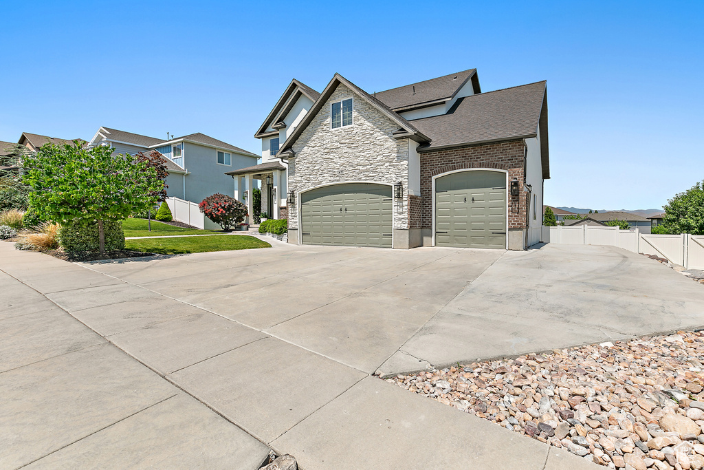 View of home\\\\\\\'s exterior featuring concrete driveway, stone siding, a garage, and roof with shingles