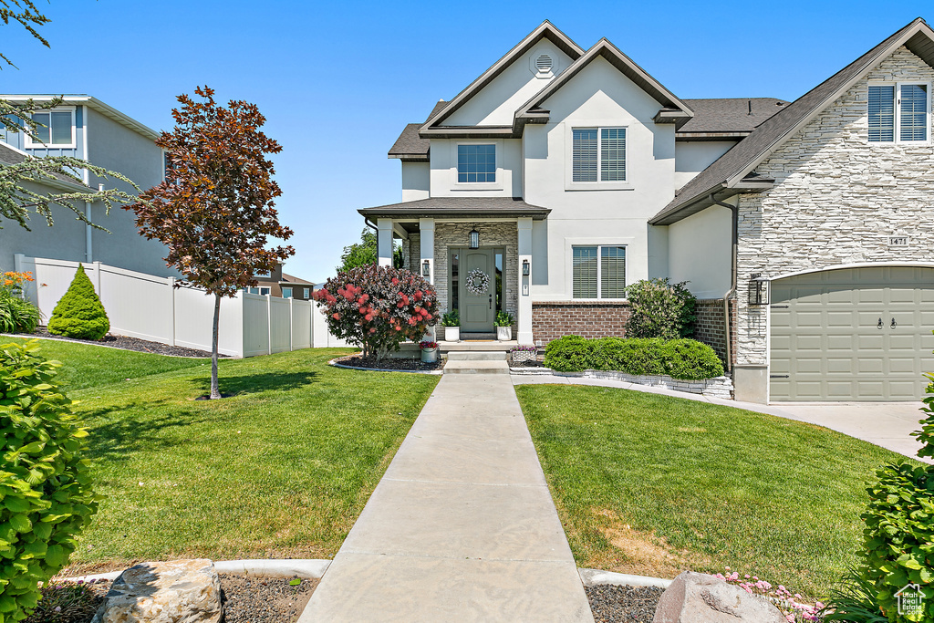Traditional home featuring stucco siding, stone siding, a garage, and concrete driveway