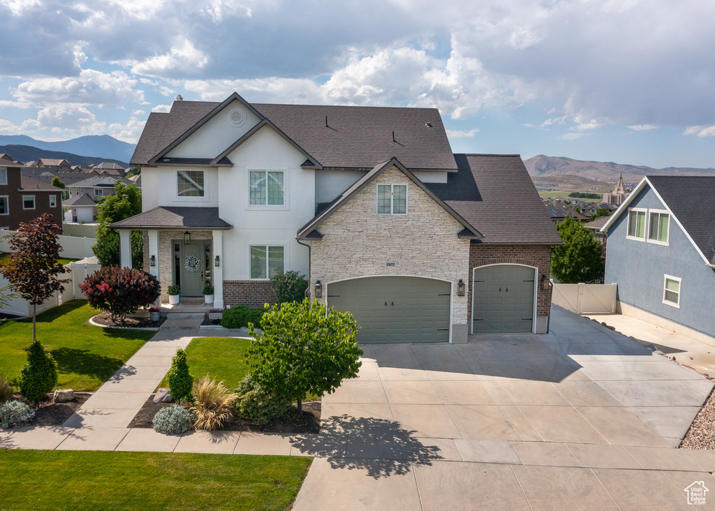 View of front facade featuring a shingled roof, a mountain view, concrete driveway, a garage, and stucco siding
