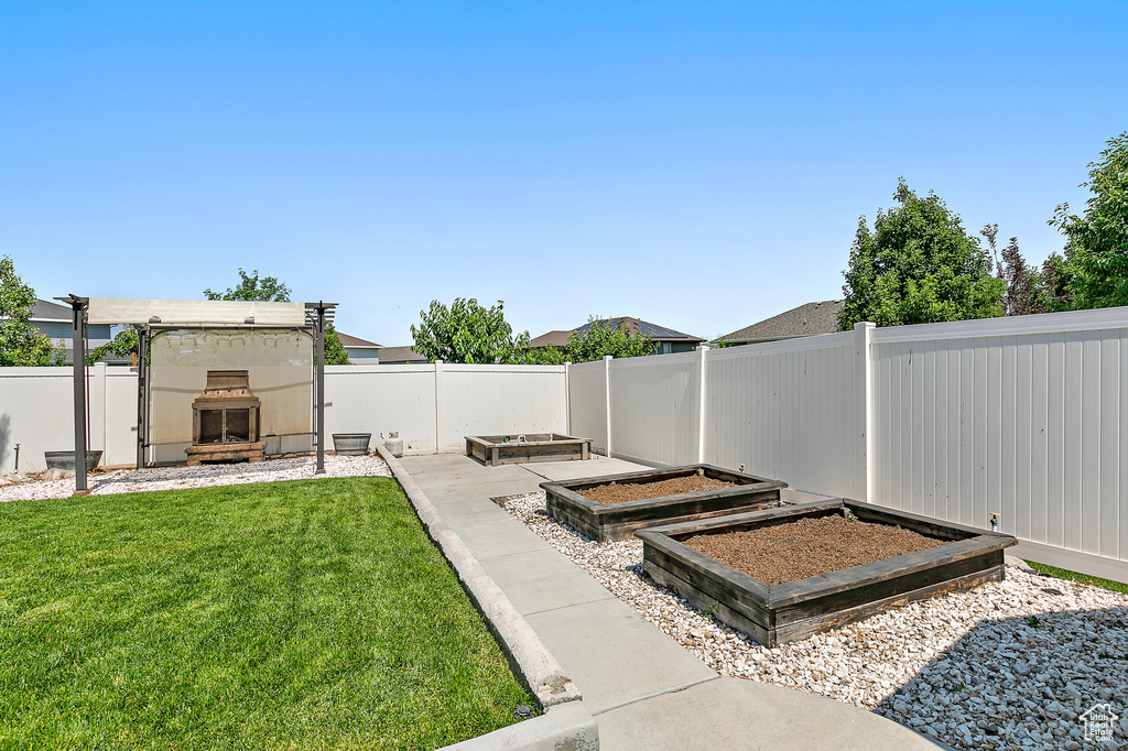 Fenced backyard with exterior fireplace and a vegetable garden