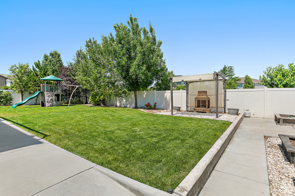 Fenced backyard featuring exterior fireplace and a patio