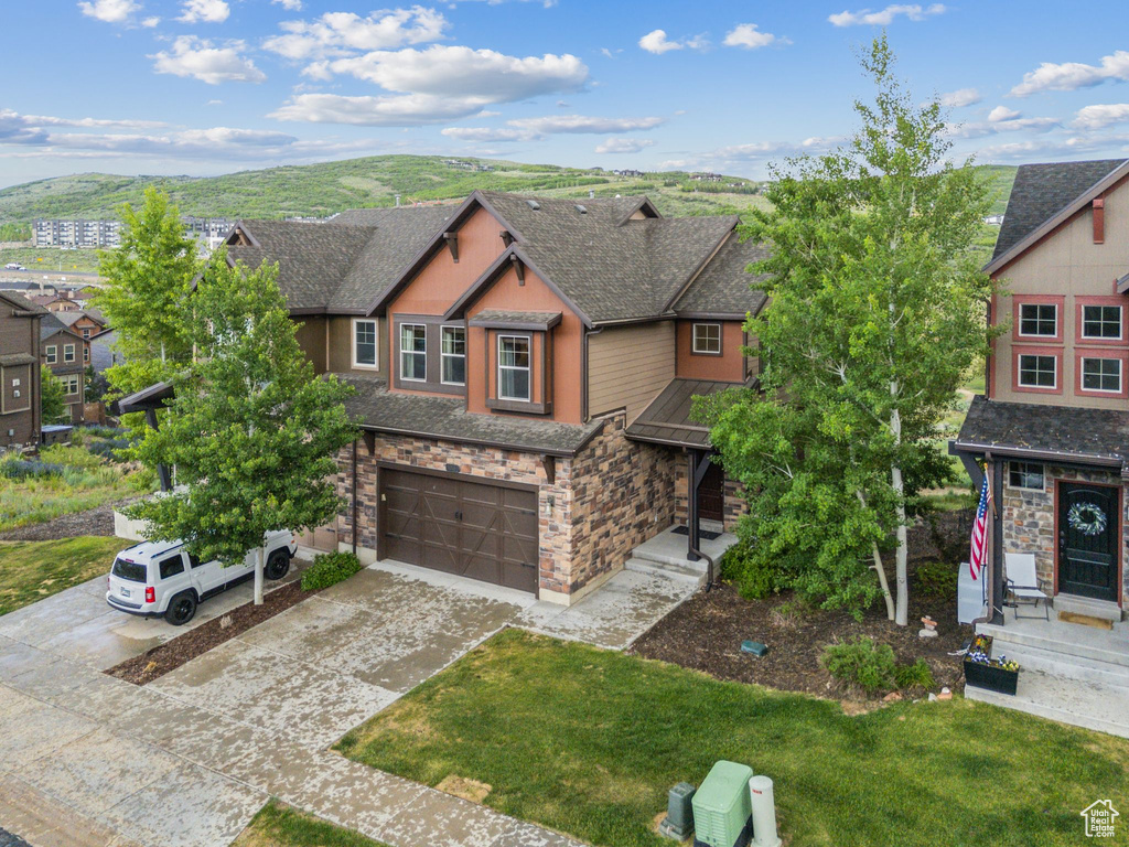 View of front of house with stone siding, an attached garage, concrete driveway, and a shingled roof