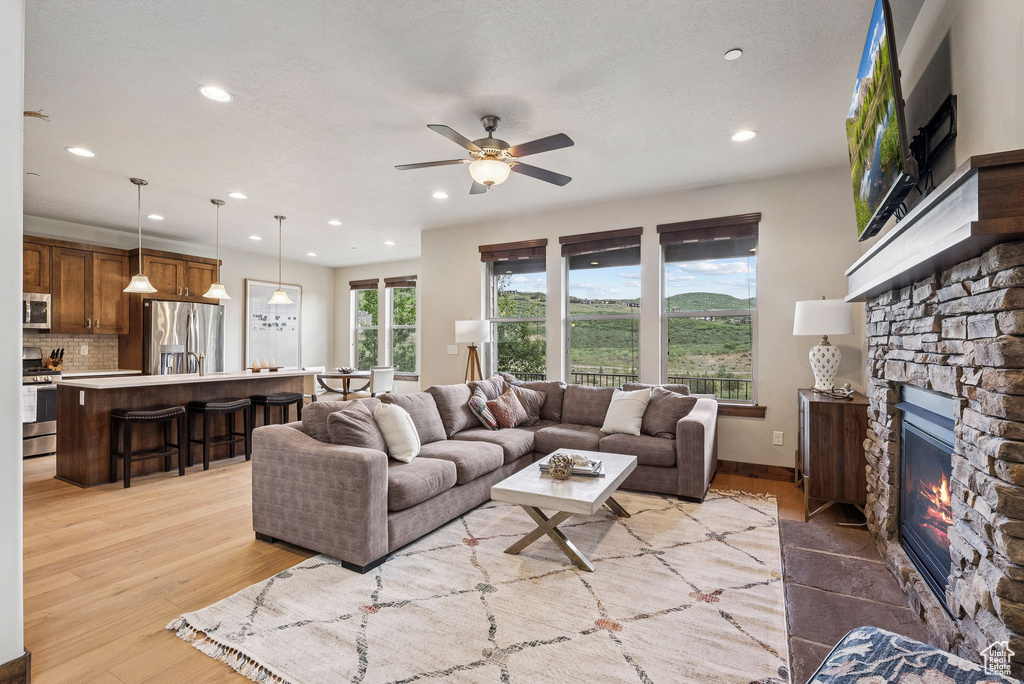Living room with recessed lighting, a fireplace, a ceiling fan, and light wood-style flooring