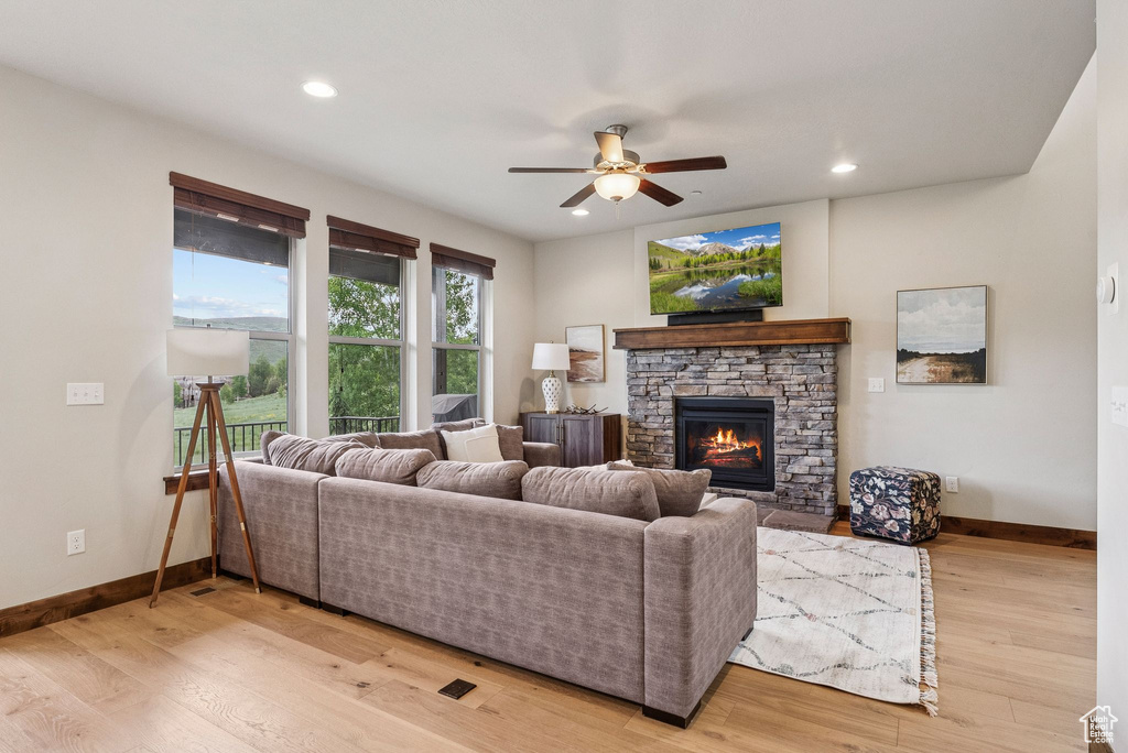 Living area featuring a ceiling fan, a fireplace, light wood-type flooring, and recessed lighting