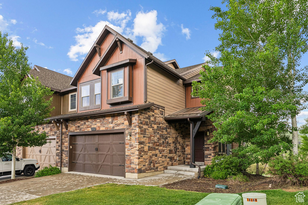Craftsman-style home with stone siding, a garage, and driveway